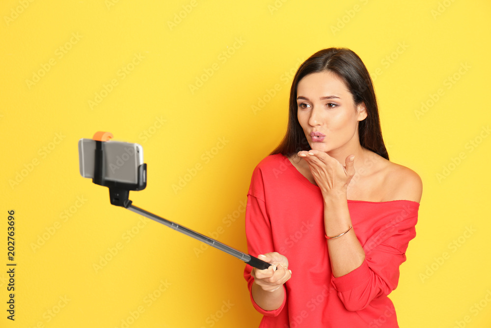 Young beautiful woman taking selfie against color background Young beautiful woman taking selfie against color background