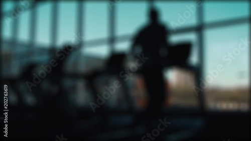 man runs on a treadmill on a window background