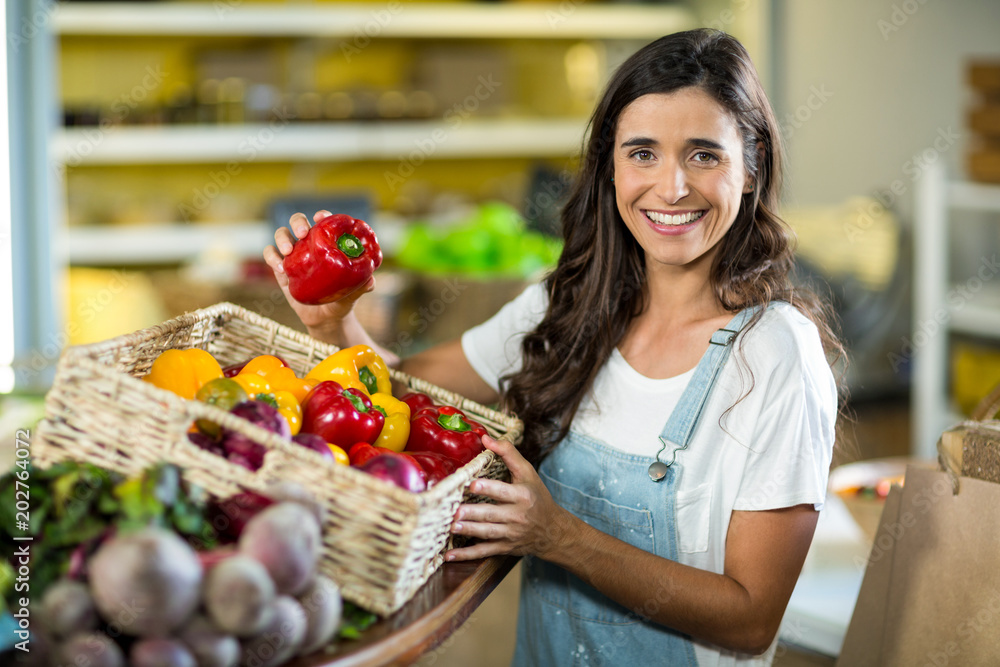 Smiling woman picking bell pepper from the basket from grocery store Smiling woman picking bell pepper from the basket from grocery store