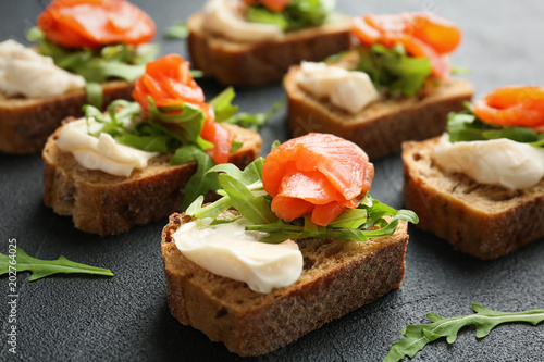 Tasty sandwiches with fresh sliced salmon fillet on table