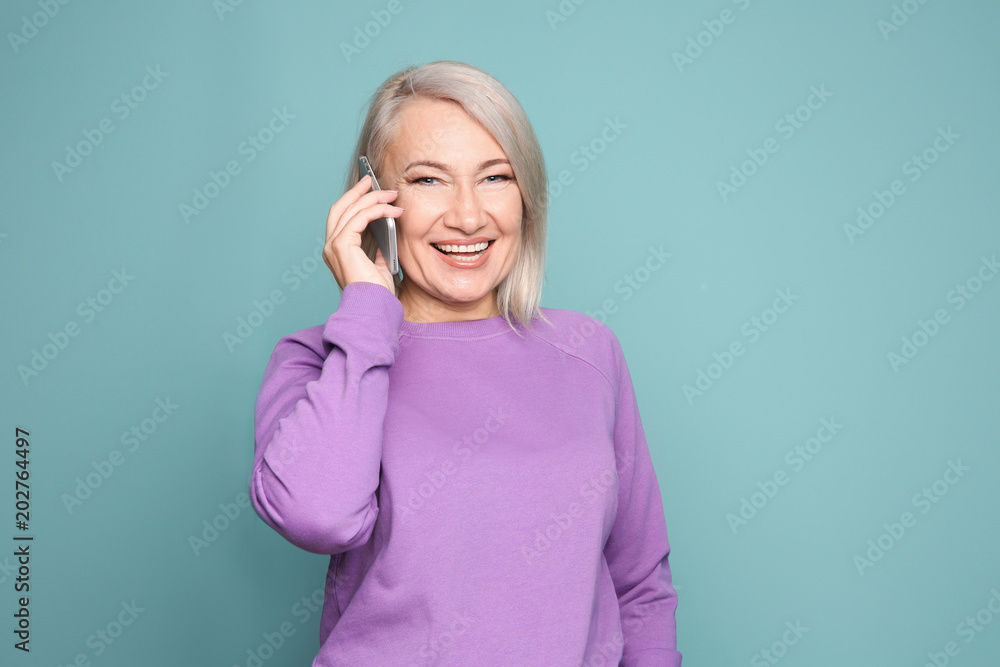 Mature woman talking on mobile phone against color background Mature woman talking on mobile phone against color background