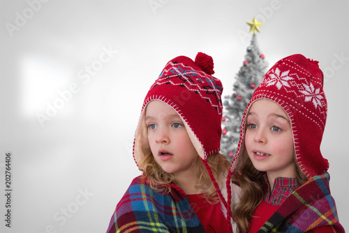 Cute girls under blanket against christmas tree in bright room