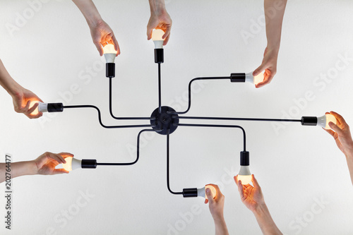 Teamwork of collective when updating LED lamps in ceiling chandelier.
