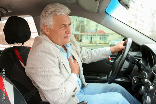 Senior man suffering from heart attack in car photo