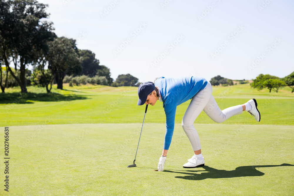 Fototapeta premium Female golfer picking up golf ball 