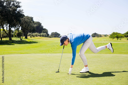 Female golfer picking up golf ball 