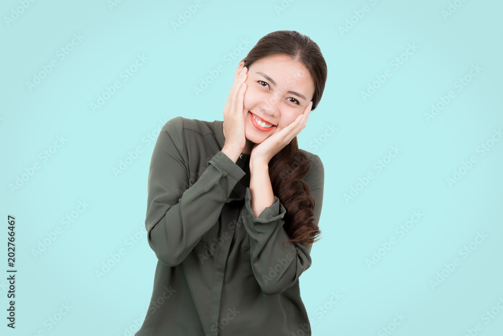 Portrait of Happy attractive fashion young Asian woman in green casual wear with smiling and touch her cheek standing on a blue pastel background. Portrait of Happy attractive fashion young Asian woman in green casual wear with smiling and touch her cheek standing on a blue pastel background.