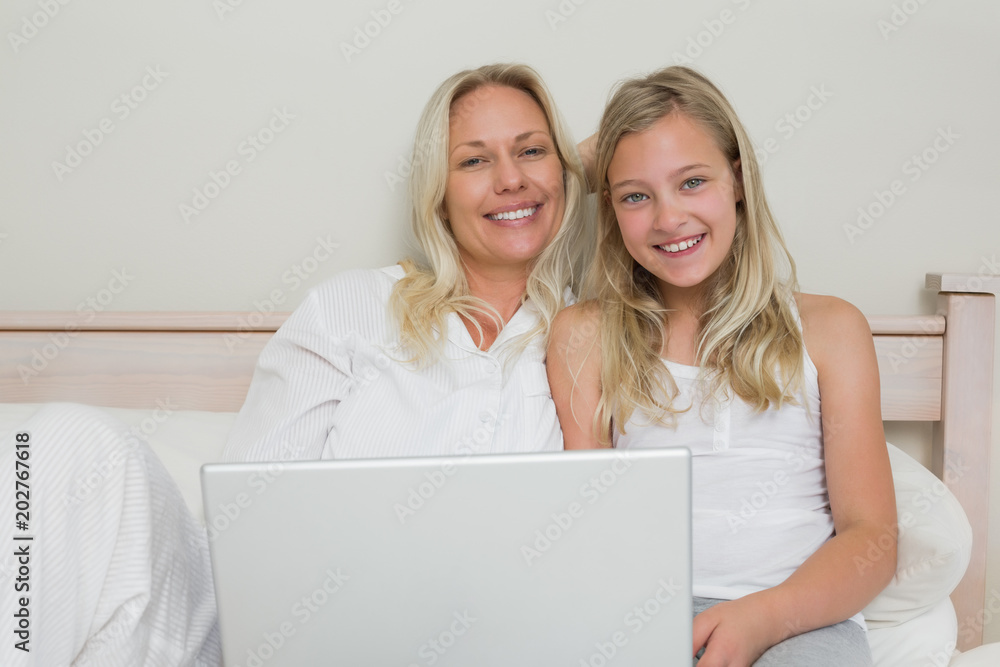 Blond mother and daughter using laptop in bed Blond mother and daughter using laptop in bed