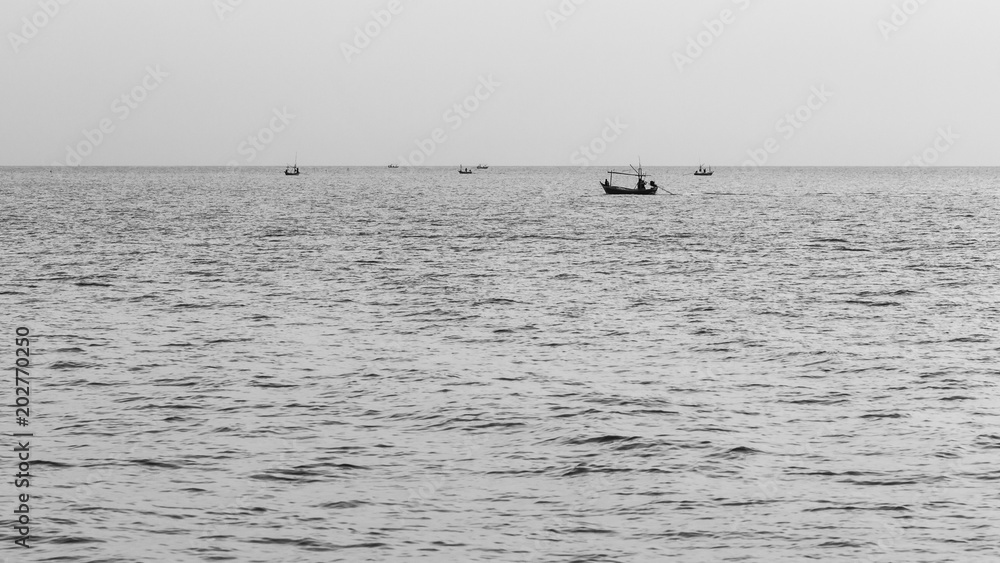 silhouette of fisherman boat in calm sea with beautiful reflection on water, black and white photography