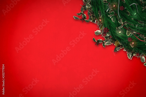 Festive christmas wreath with decorations against red background