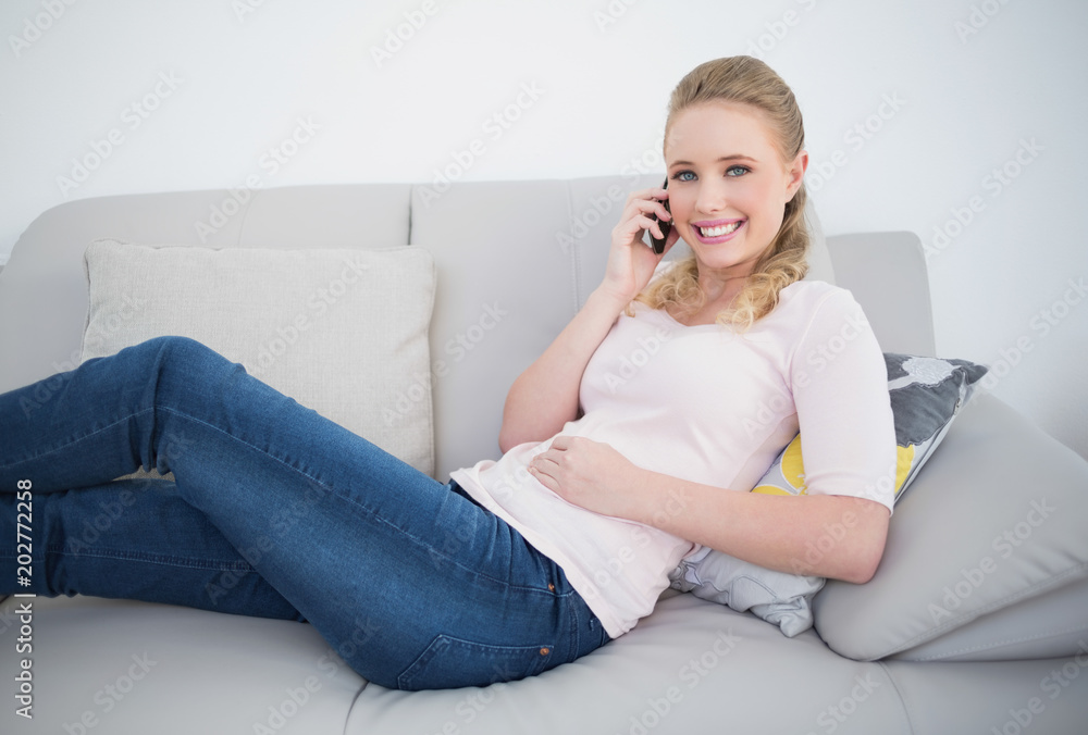 Casual smiling blonde phoning and lying on couch Casual smiling blonde phoning and lying on couch