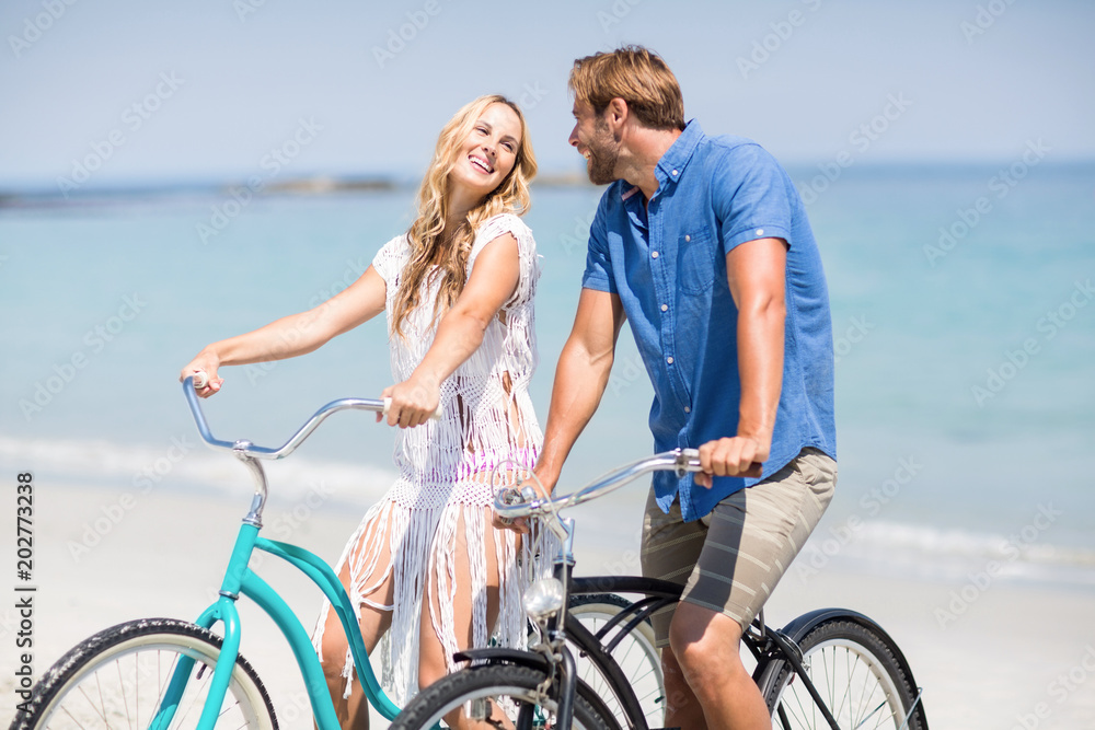 Couple riding bicycles at beach