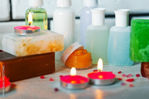Photo of bathrooms  spa treatments. Transparent bottles  loofah  pieces of soap  bath salts  candles. Comfort and relaxation