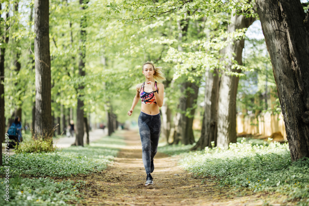 Runner athlete running at cityl park. Young woman fitness jogging workout wellness concept.