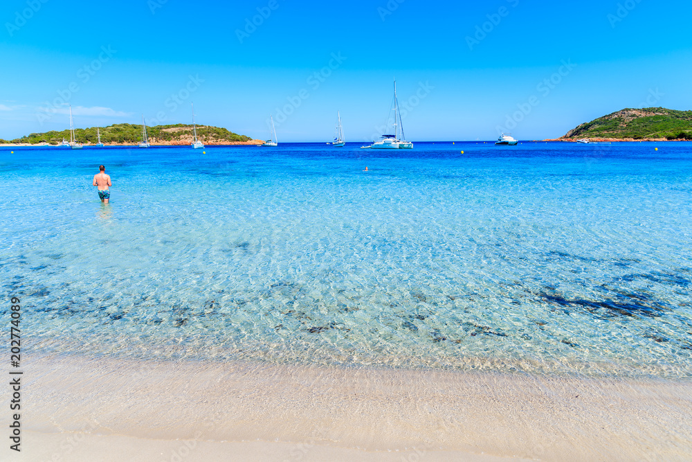 Unidentified man tourist walking into water on Santa Giulia beach, Corsica island, France Unidentified man tourist walking into water on Santa Giulia beach, Corsica island, France