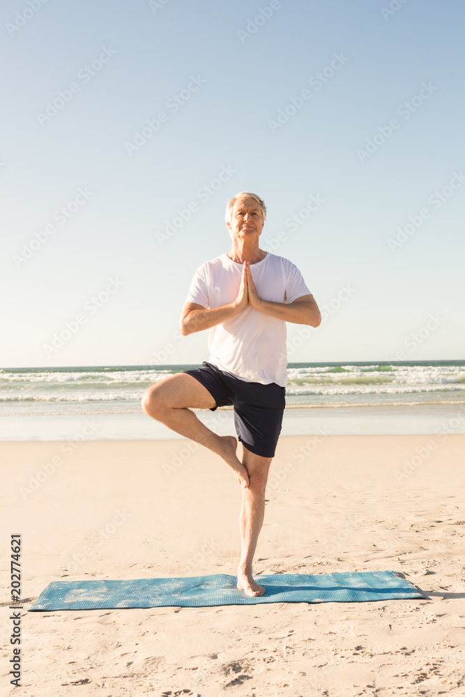 Active senior man practicing tree pose at beach Active senior man practicing tree pose at beach