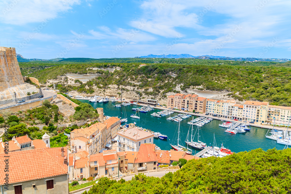 BONIFACIO PORT, CORSICA ISLAND - JUN 24, 2015: View of beautiful port with colorful houses and boats on sunny summer day. This French island is popular tourist destination in Europe.