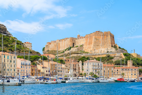 BONIFACIO PORT, CORSICA ISLAND - JUN 25, 2015: sailing yacht boats anchoring in Bonifacio port with citadel building in background. It is famous old town built on top of a cliff.