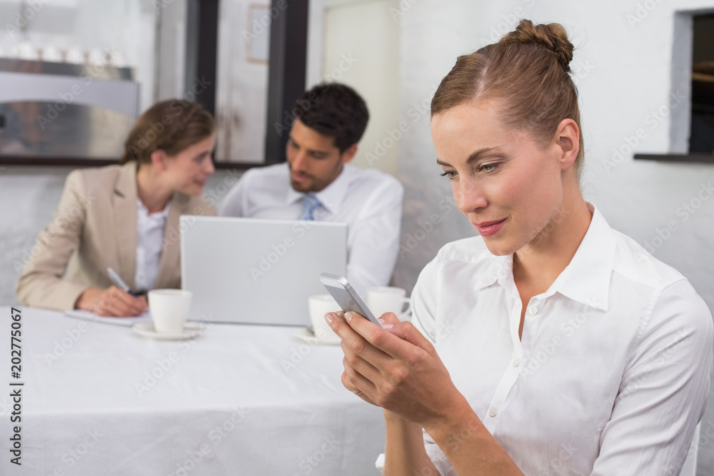 Businesswoman text messaging with colleagues at office desk Businesswoman text messaging with colleagues at office desk