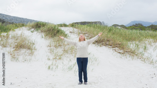 Senior woman with arms outstretched at beach