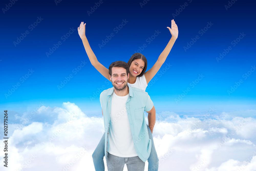 Happy casual man giving pretty girlfriend piggy back against blue sky over clouds Happy casual man giving pretty girlfriend piggy back against blue sky over clouds