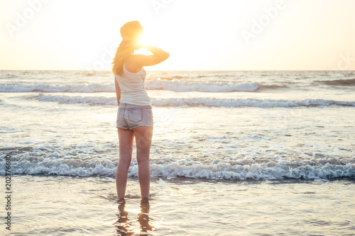 beautiful and young woman looks at the sunset beach