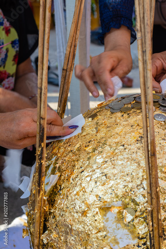 People try to stick a gold leave on buried stone when thai traditional Fung Luuk Nimit photo