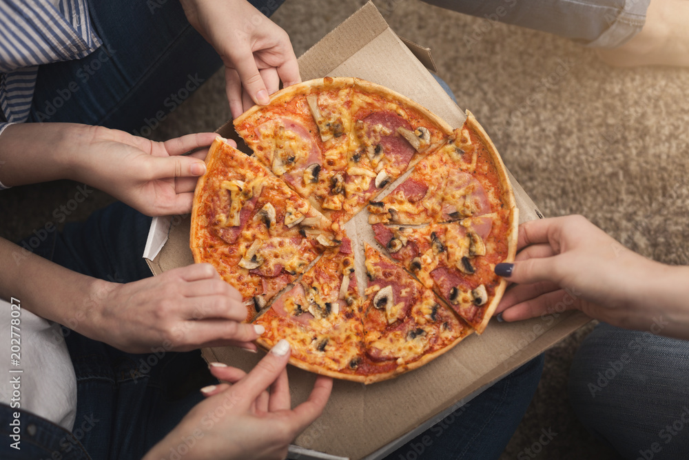 Closeup of three girl friends taking pizza slices Closeup of three girl friends taking pizza slices