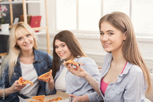 Closeup of three girl friends eating pizza at home