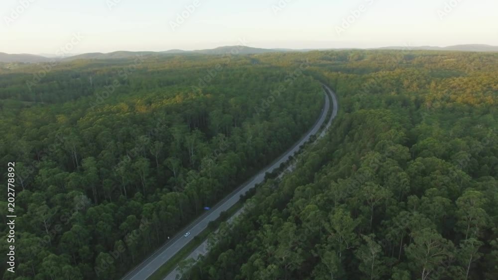 Static aerial view of cars driving on highway in scenic rural area at sunset Static aerial view of cars driving on highway in scenic rural area at sunset