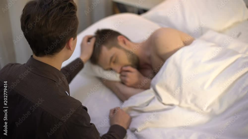 Young man stroking sleeping partner head, homosexual couple, tender relations Young man stroking sleeping partner head, homosexual couple, tender relations