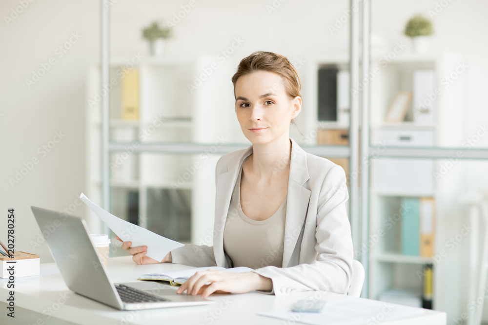 Serious female manager looking at you while working with documents and organizing work Serious female manager looking at you while working with documents and organizing work