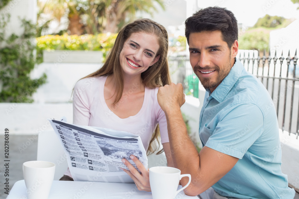 Smiling couple reading newspaper at café Smiling couple reading newspaper at café