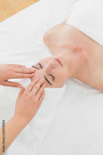 Hands massaging womans forehead at beauty spa