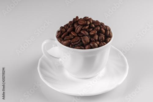 Coffee cup filled wit coffee beans isolated on white background.