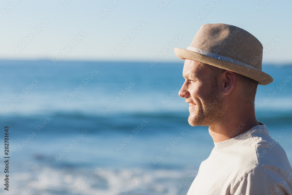 Handsome man wearing straw hat looking at the sea
