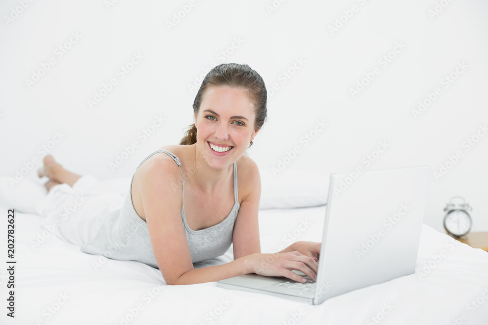 Smiling casual woman using laptop in bed Smiling casual woman using laptop in bed