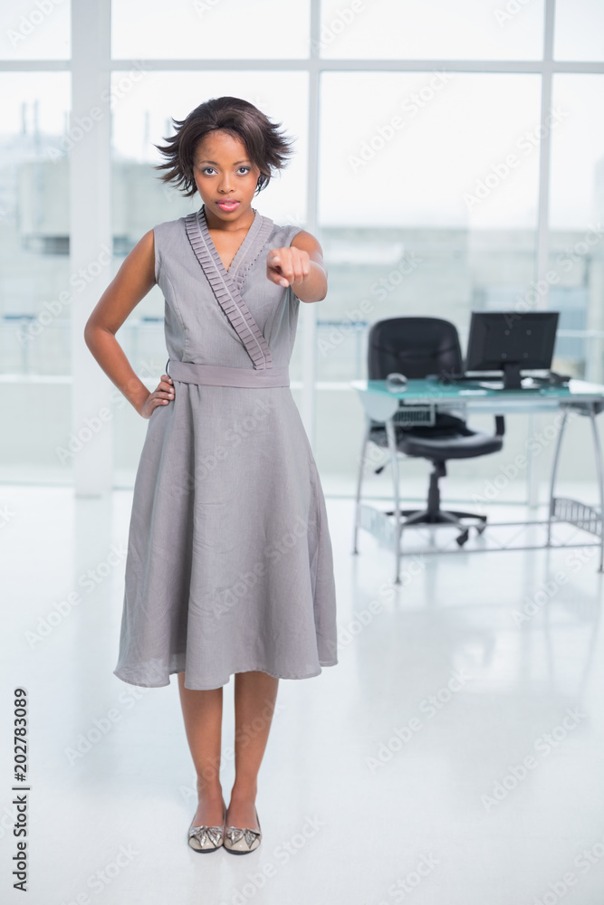 Serious businesswoman standing in her office and pointing Serious businesswoman standing in her office and pointing