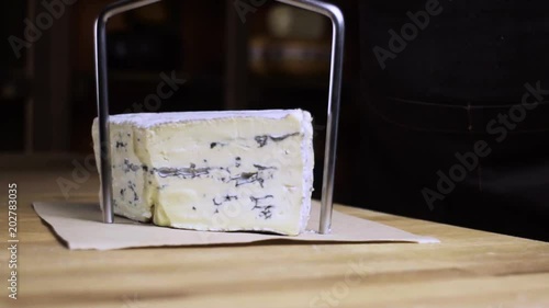 Blue cheese is cut with a cheese knife. Cheese shop. Cheese with blue mold. Slow motion. photo