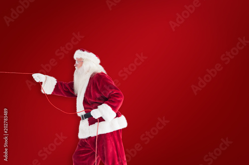 Santa pulls something with a rope against red background