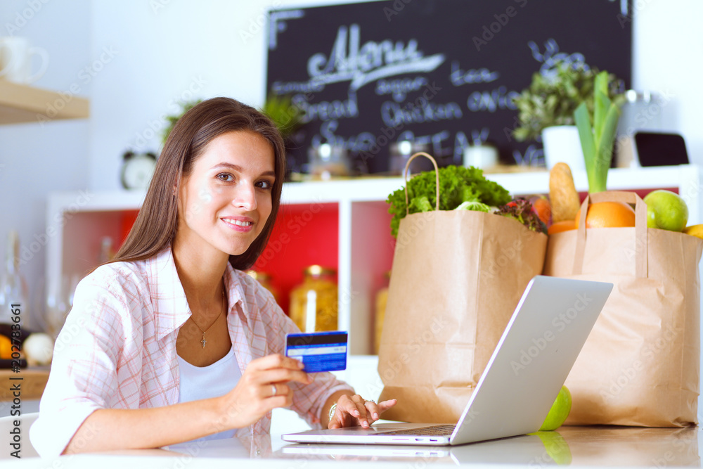 Smiling woman online shopping using tablet and credit card in kitchen . Smiling woman Smiling woman online shopping using tablet and credit card in kitchen . Smiling woman