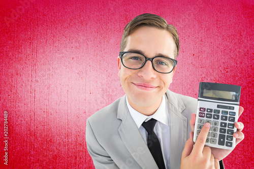 Geeky smiling businessman showing calculator against weathered surface 