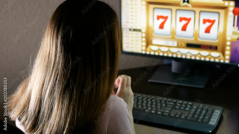Young woman won in an online casino and coins pour out directly from the monitor. Brunette is very happy about her luck in gambling. Young woman won in an online casino and coins pour out directly from the monitor. Brunette is very happy about her luck in gambling.