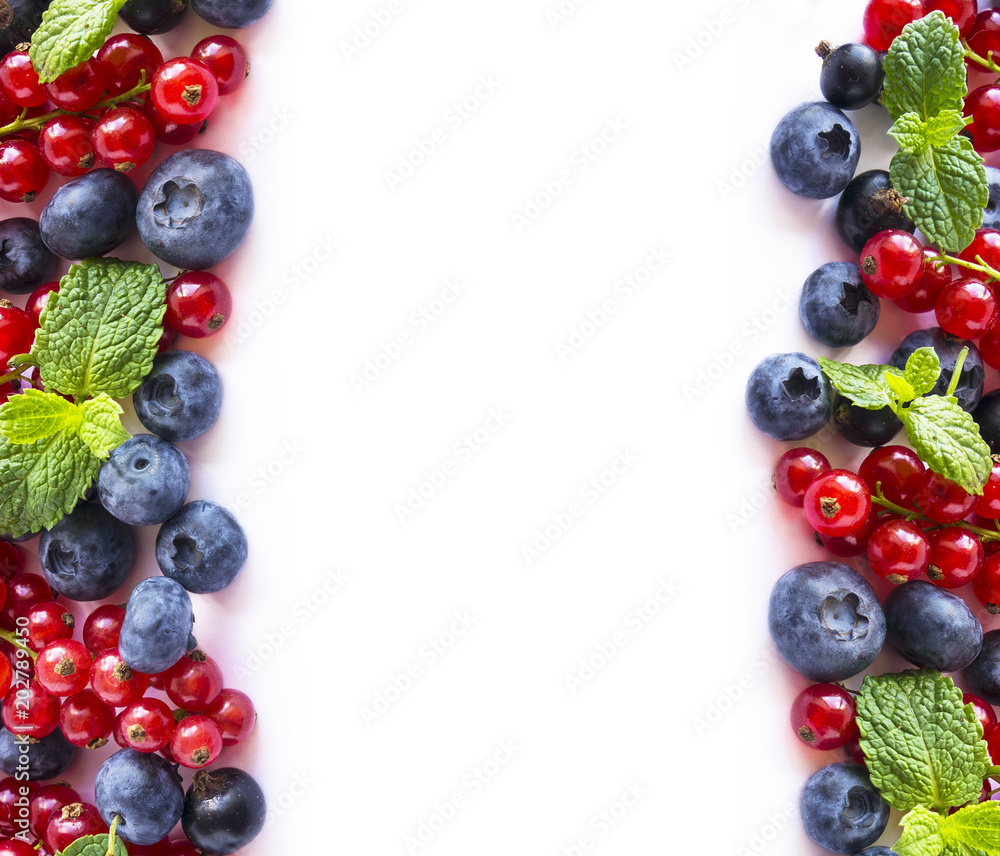 Mix berries and fruits at border of image with copy space for text. Ripe blueberries, red and black currants with mint leaves on white background. Top view. Mix berries and fruits at border of image with copy space for text. Ripe blueberries, red and black currants with mint leaves on white background. Top view.