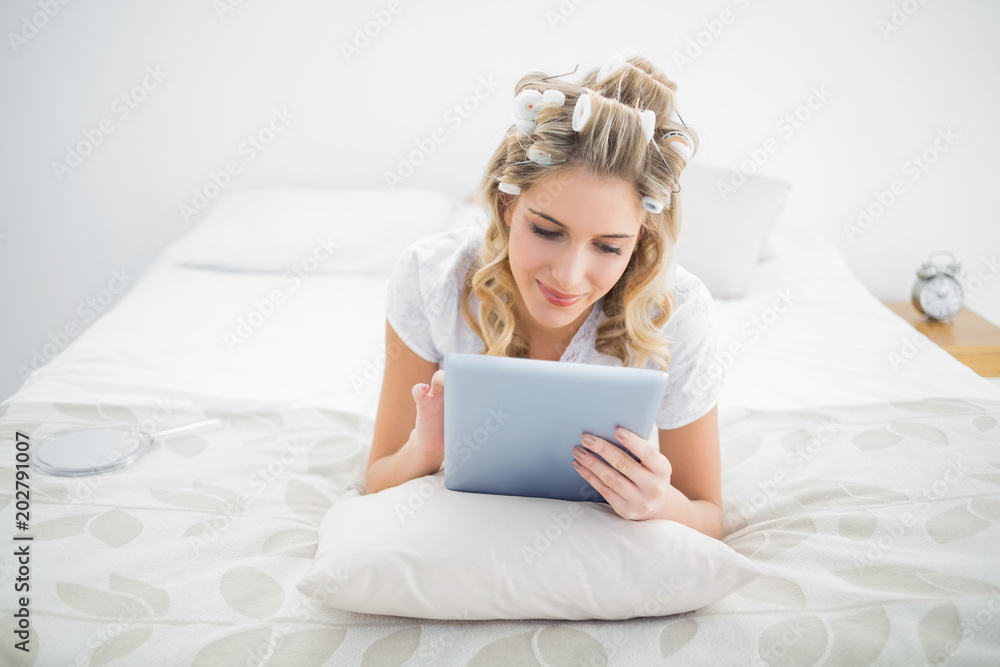 Peaceful pretty blonde wearing hair curlers using tablet pc Peaceful pretty blonde wearing hair curlers using tablet pc