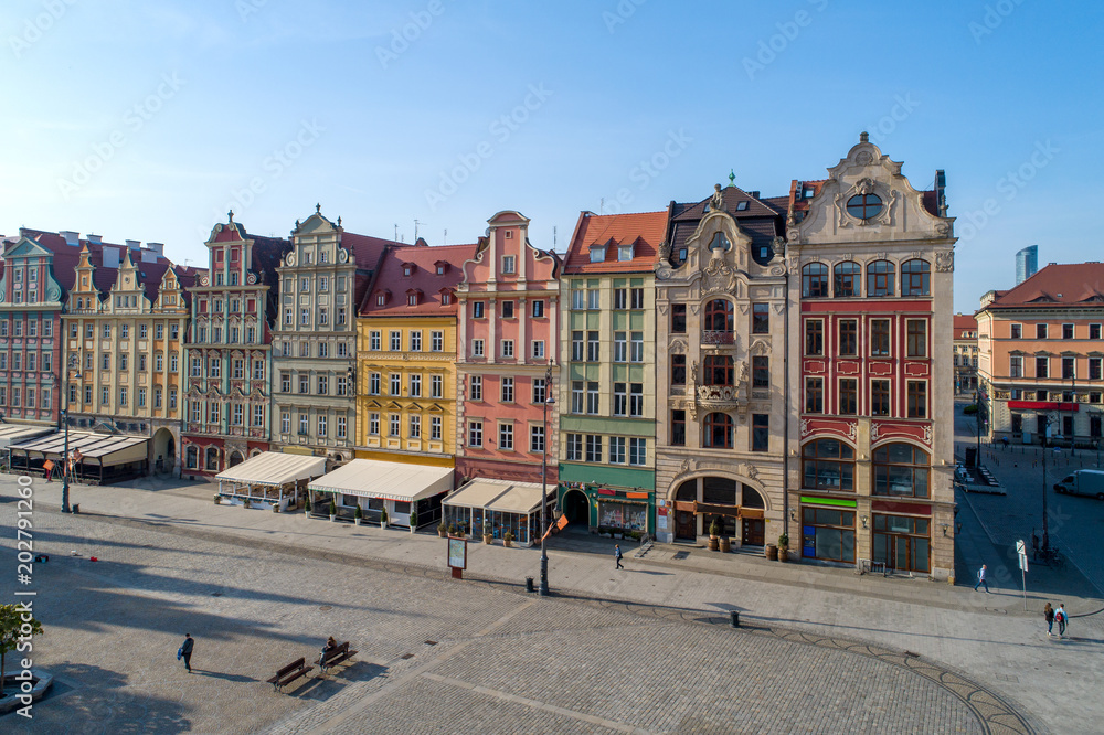 Poland, Wroclaw. Market Square (Rynek) with old historic tenements and outdoor restaurants. Aerial view. Early morning