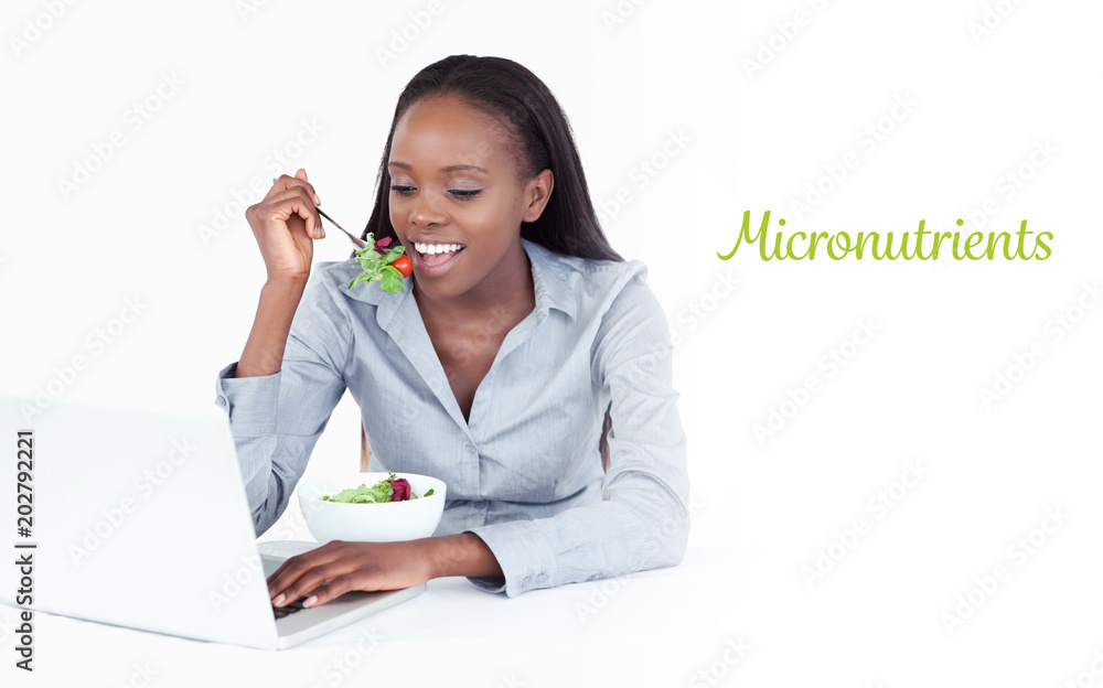 The word micronutrients against businesswoman working with a laptop while eating a salad The word micronutrients against businesswoman working with a laptop while eating a salad