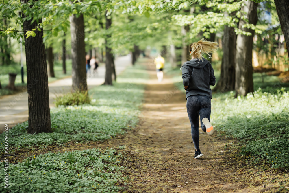 Young girl jogging in the park along trees Young girl jogging in the park along trees