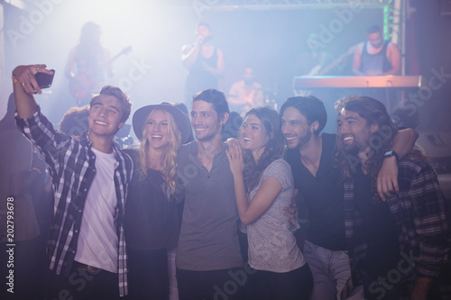 Smiling friends taking selfie in nightclub