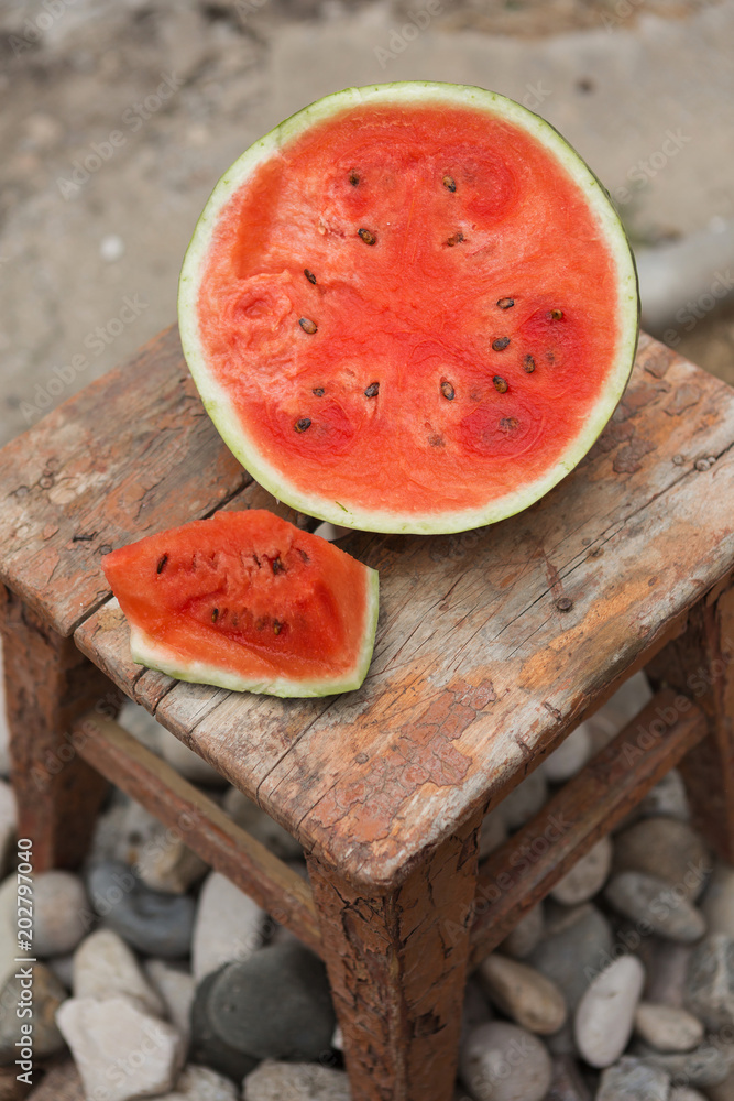 on an old stool a cut watermelon, a floor of a water-melon and a slice, a  red pulp Stock Photo | Adobe Stock